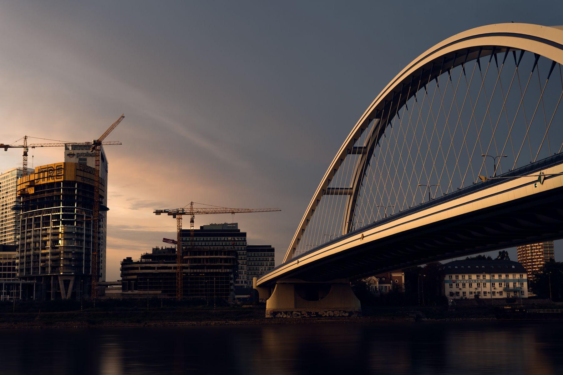 Bridge and construction cranes at dusk